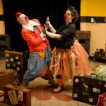 Clowns performing indoors with vibrant costumes and stage props, capturing joyful fun.