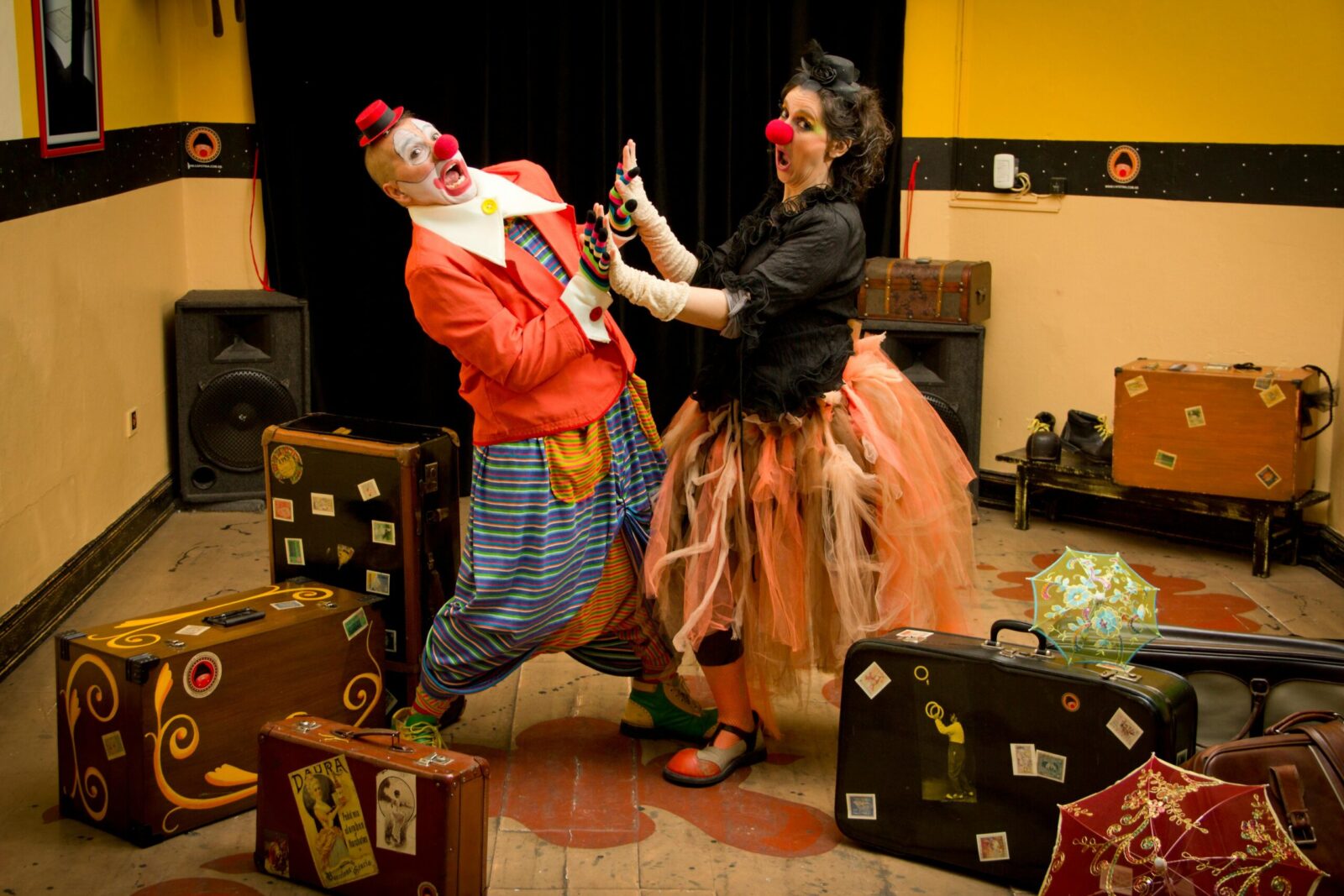 Clowns performing indoors with vibrant costumes and stage props, capturing joyful fun.